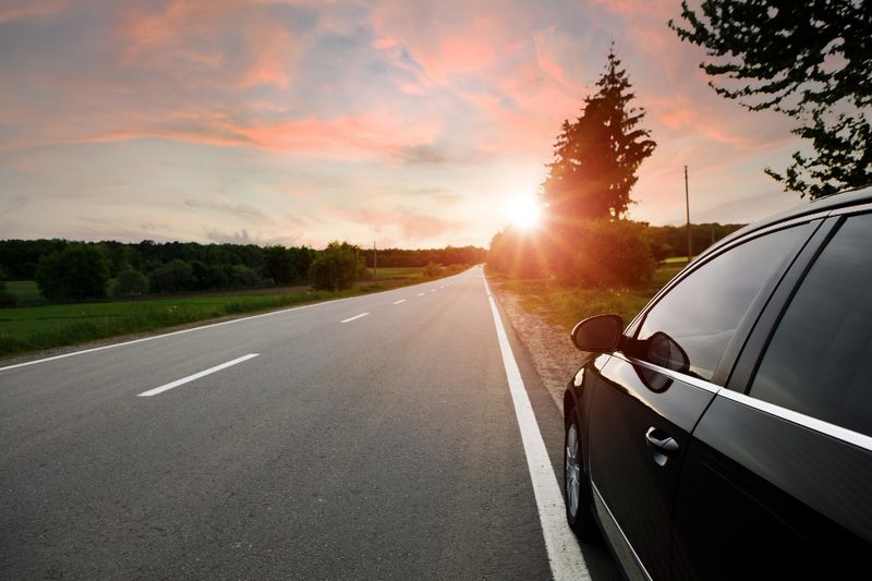 Berline noire sur une route dégagée au lever du soleil